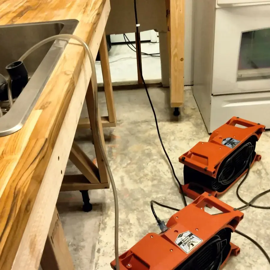 Orange air movers lined up along the counters of a Federal Heights kitchen with a stained floor