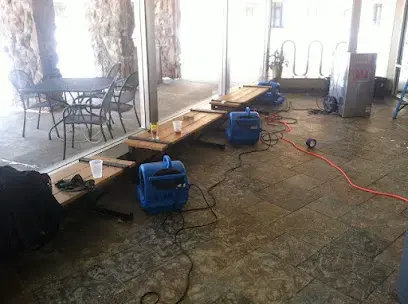 Blue air movers running on a wet floor with the furniture pushed to the side