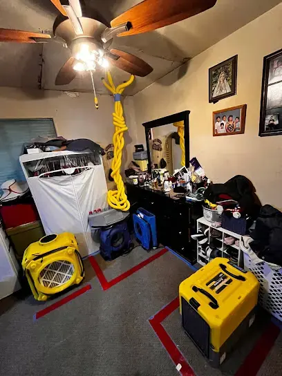 Bedroom where yellow dehumidifiers and air movers are working after a leak