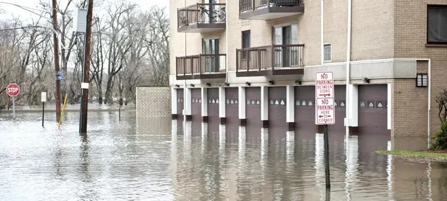 Floodwater covering a street and the ground floor of an apartment building