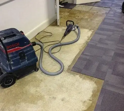 Portable extractor and wand pulling water out of wet carpet tiles